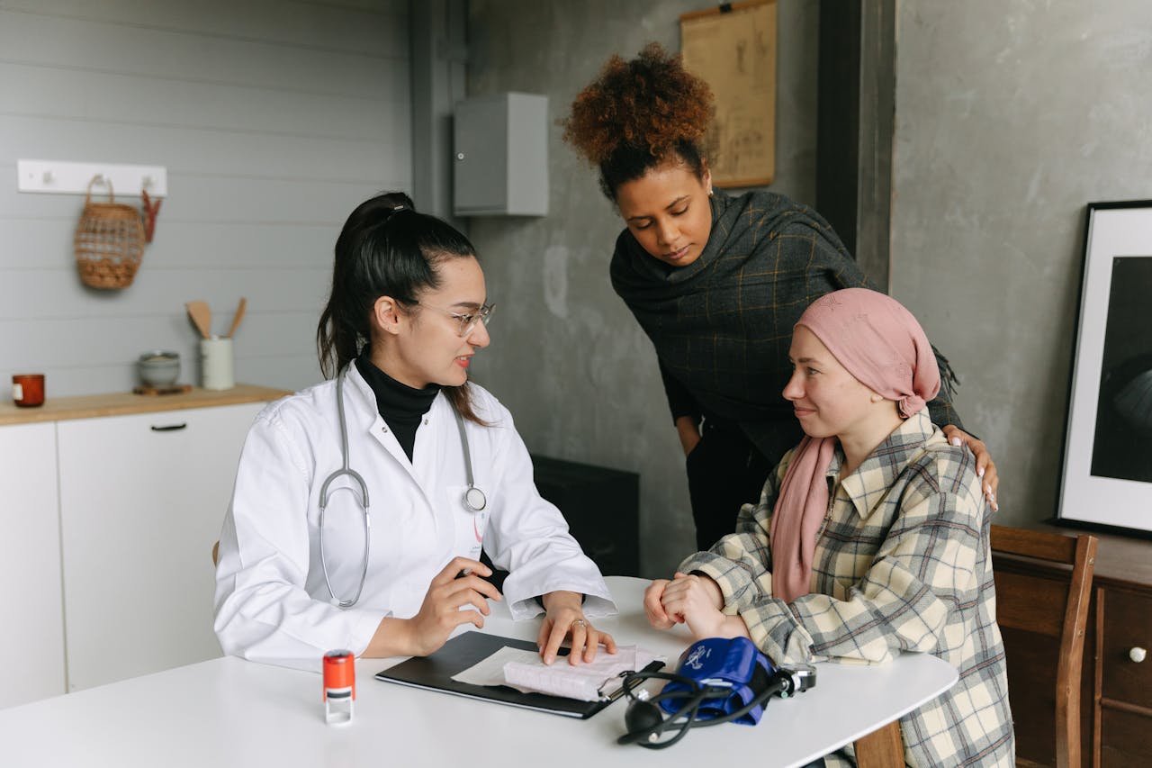 A doctor consulting with cancer patient and friend at home, offering support.